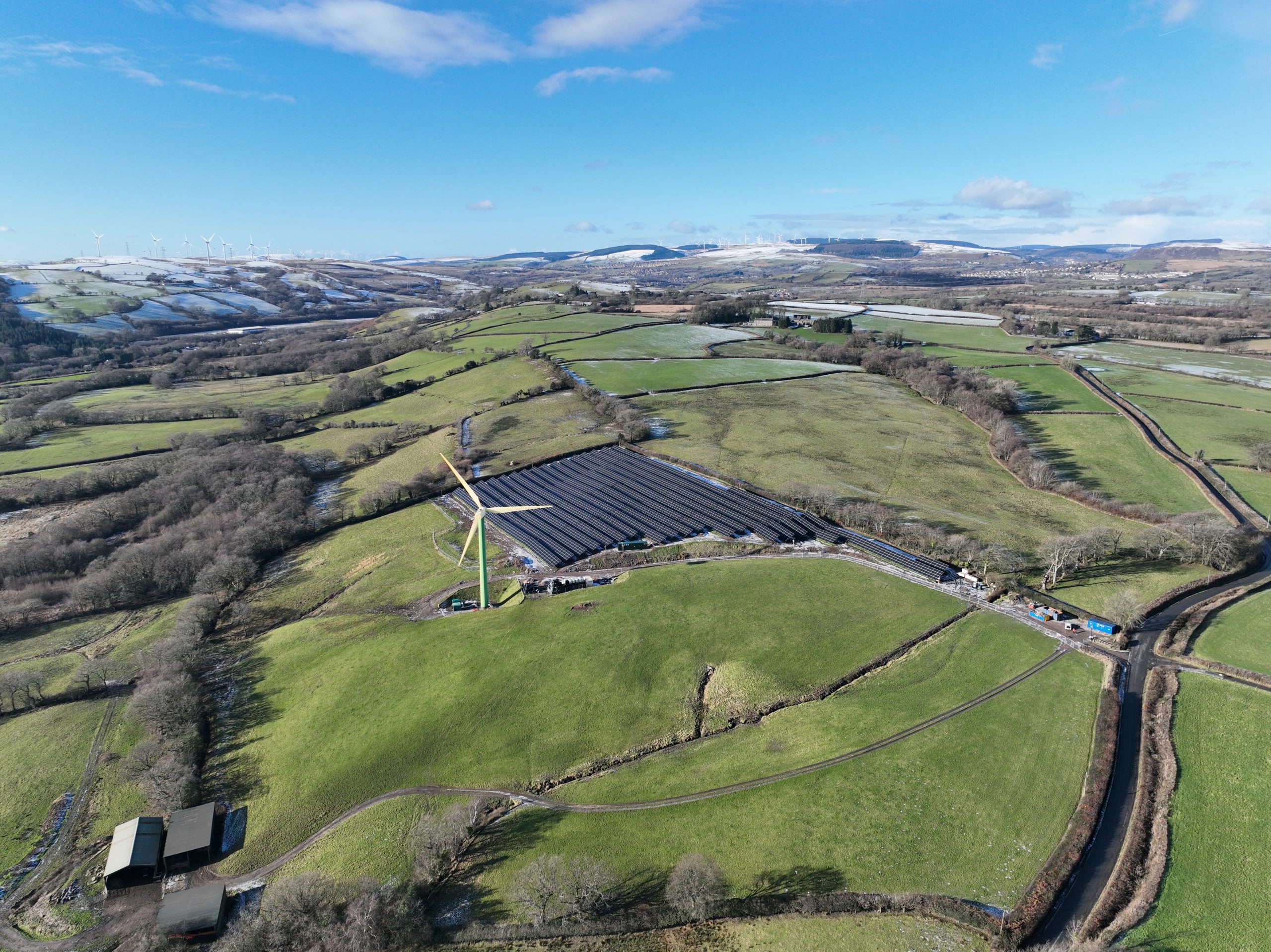 an aerial image of a solar farm in the uk next to a wind generator
