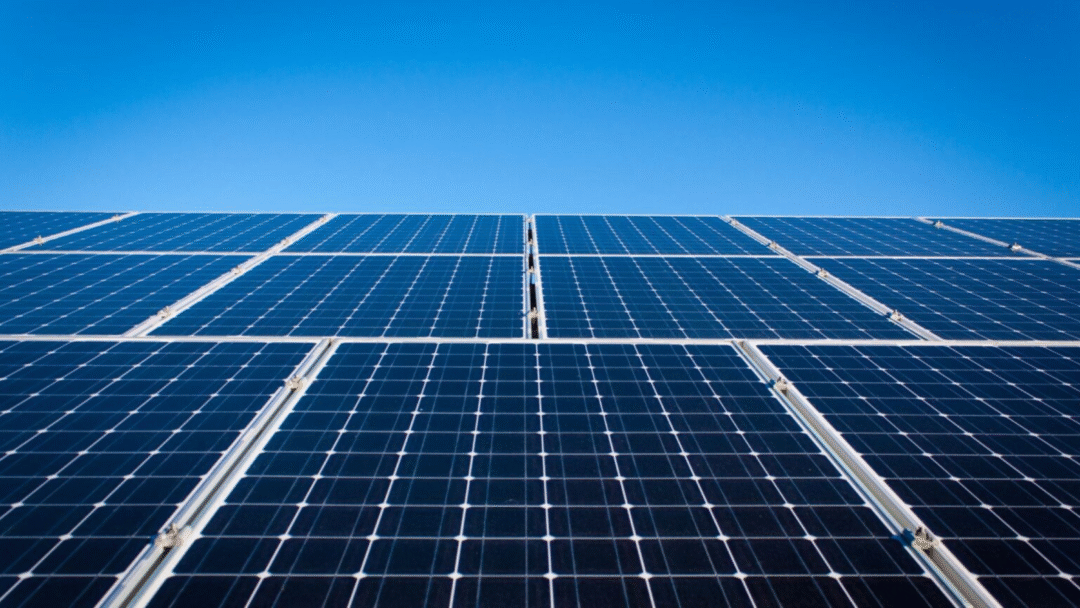 Close-up view of large blue solar panels under a clear blue sky.
