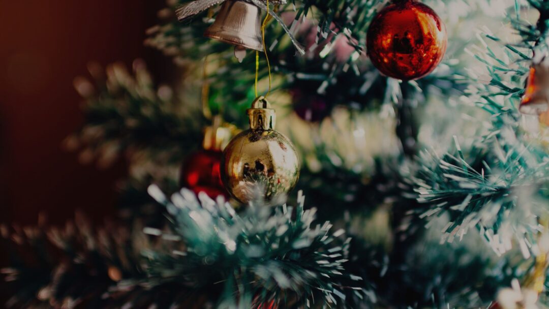 Close-up of Christmas tree ornaments with gold and red baubles.