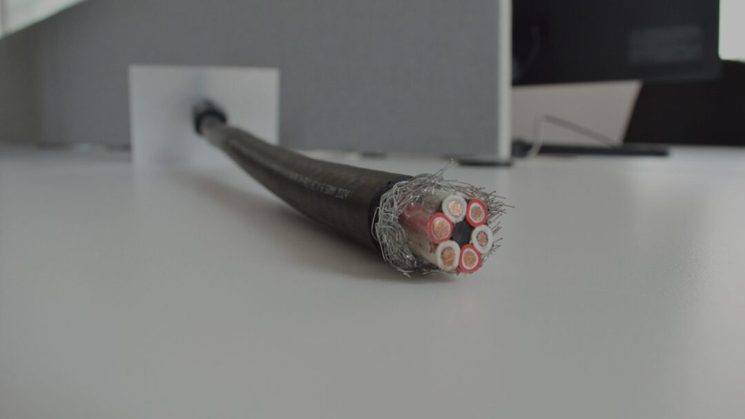 Close-up of a multi-core electrical cable with exposed copper conductors on a desk.