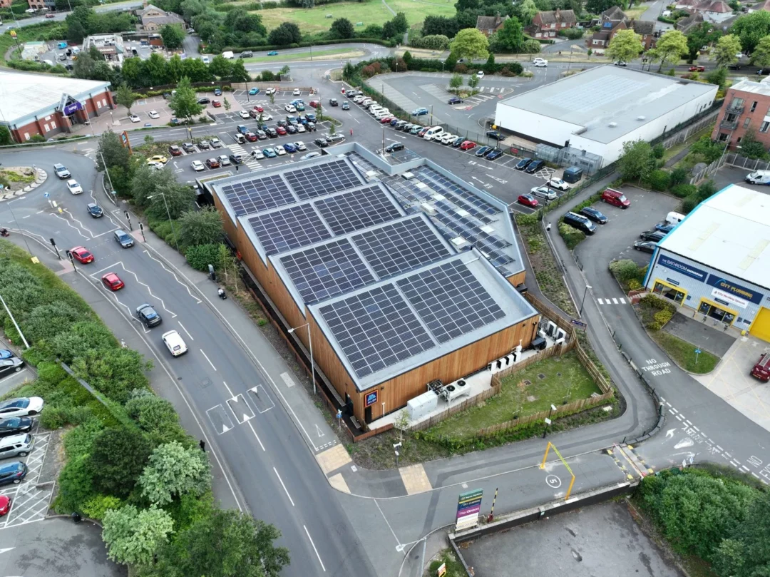 Aerial view of a commercial building with a large rooftop solar PV system in a busy urban area.