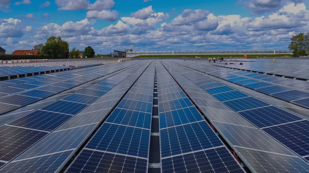 Ground-mounted solar panels against a backdrop of blue sky and scattered clouds.
