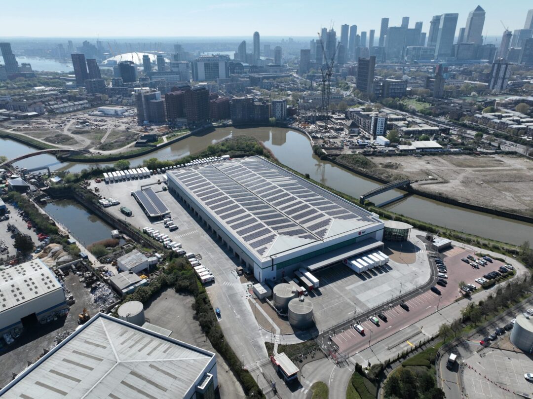 High-resolution view of a DPD warehouse in an urban setting with a complete rooftop solar panel installation overlooking a canal.