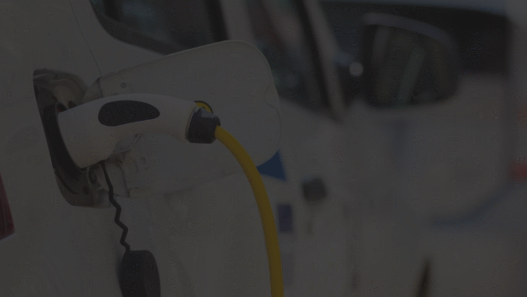 Electric vehicle plugged into a charging station with a yellow charging cable.
