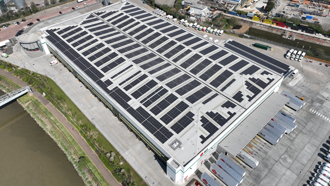 Large distribution centre with rooftop solar panels installed at scale, representing solar for business in logistics and warehousing