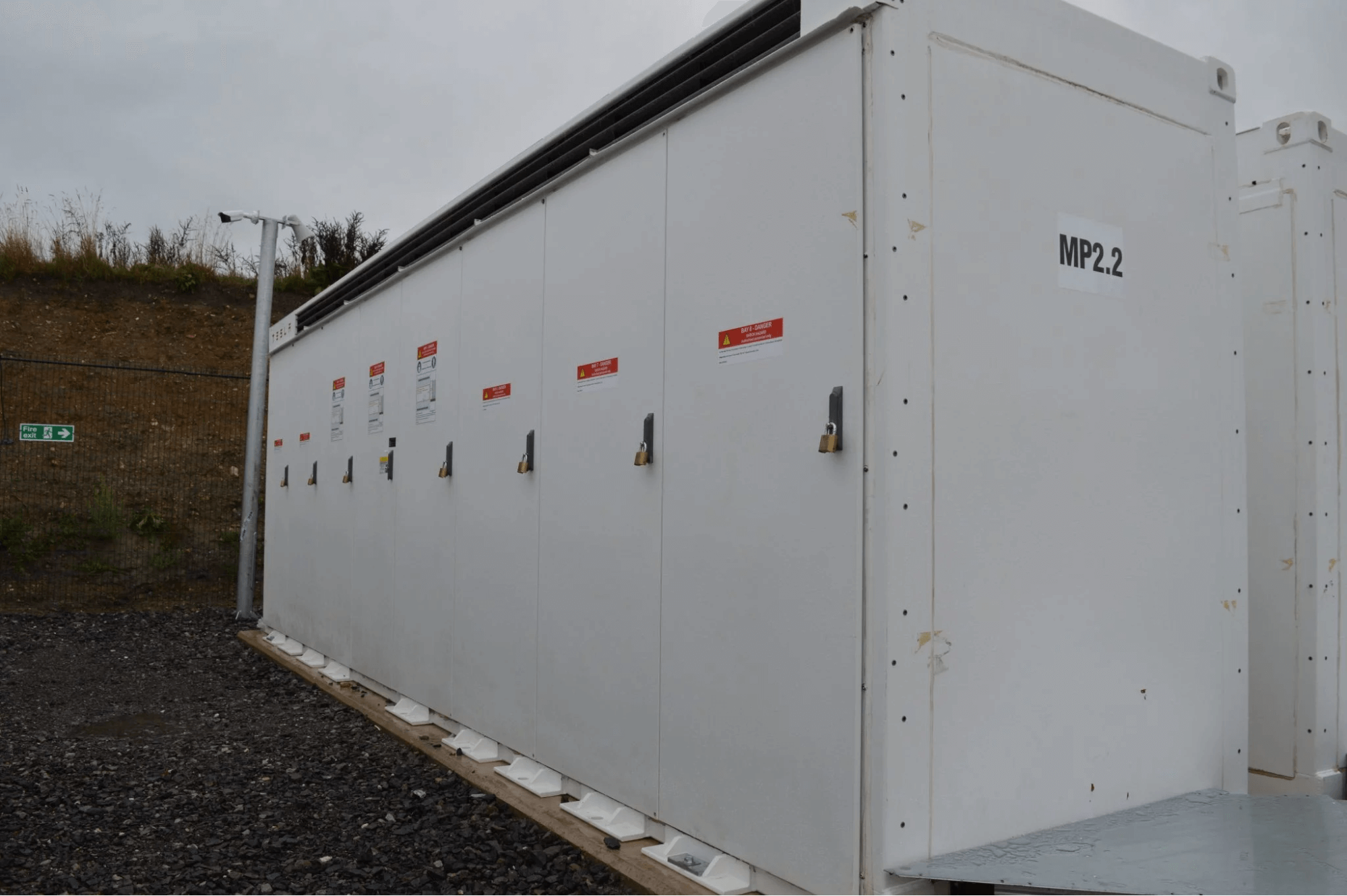 Locked commercial battery storage systems installed in a secure compound, used for renewable energy management.