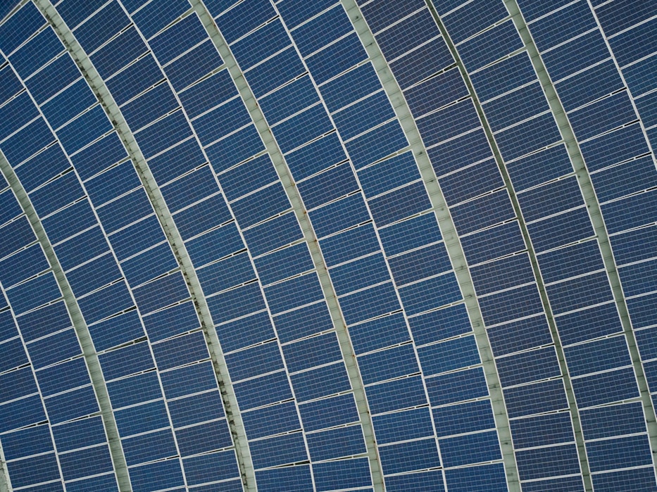 Aerial view of curved rows of solar panels arranged in parallel arcs on a large structure.