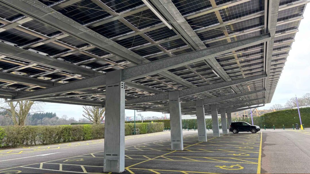 Underneath view of a solar carport structure with integrated solar panels above accessible parking bays, combining renewable energy generation with sheltered vehicle parking Paultons Park