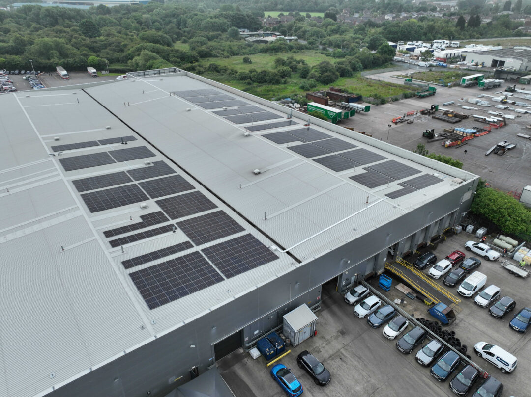 Side view of Arnold Clark’s facility showing rooftop solar panel installation above vehicle loading bays and operational yard.