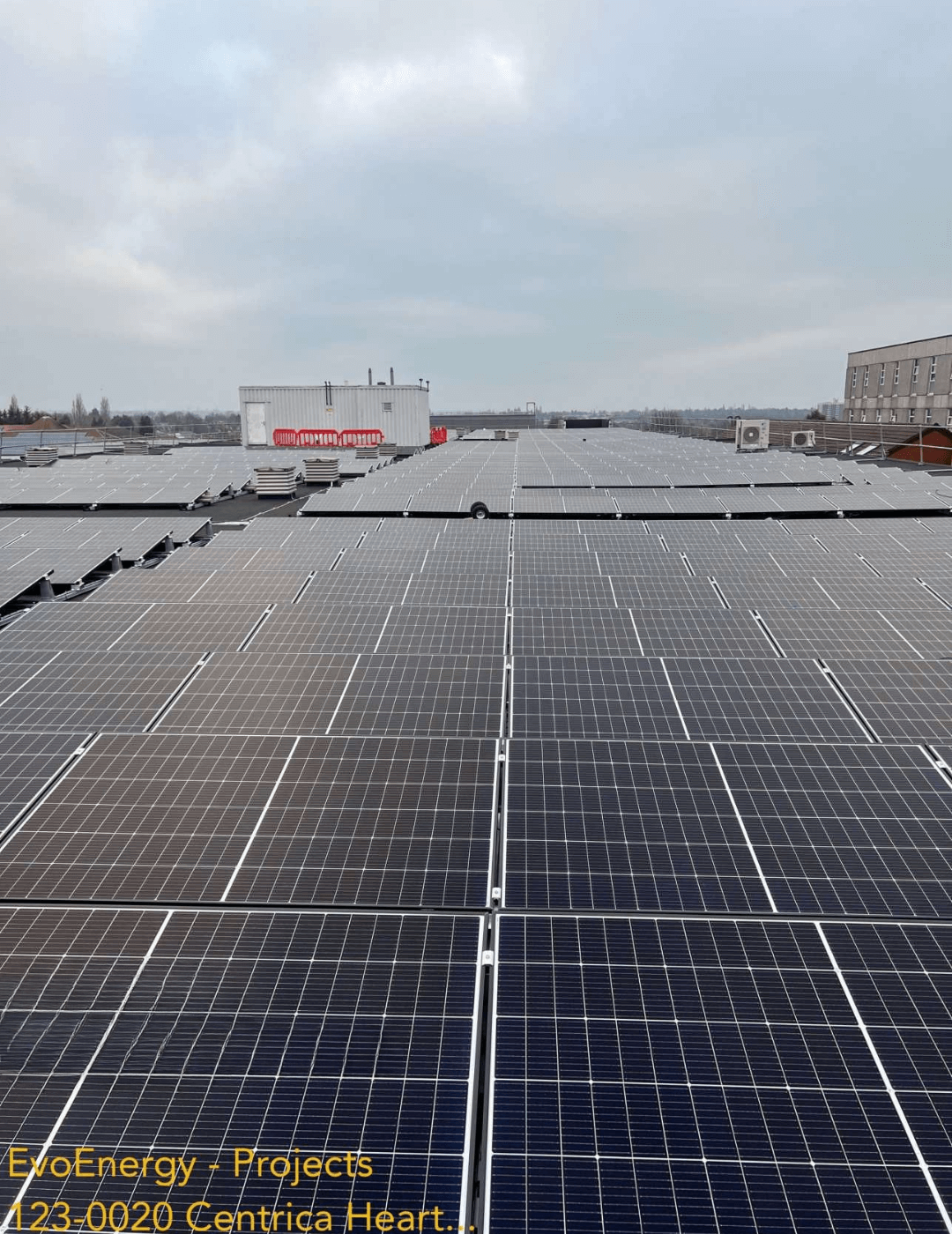 Wide rooftop view showing the solar panel installation at Heartland Hospital, with grey panels extending across the flat roofline.